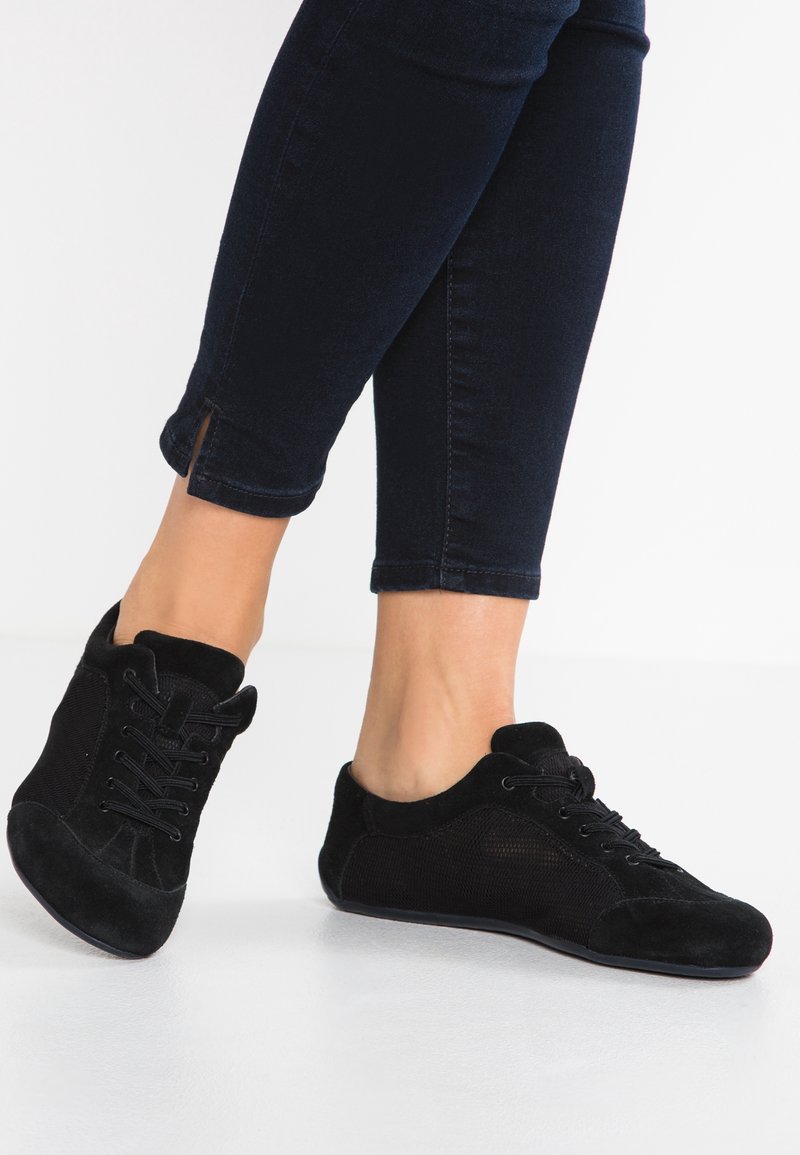 Svarta skor i mocka och mesh, med rund tå, snörningsdesign och låg profil. Bärs med mörka avklippta jeans.