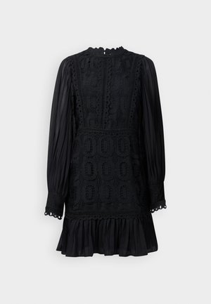 Vestido preto com mangas longas e pregueadas, detalhes intrincados em renda, barra com babados e decote com bordas. Um fecho éclair está localizado nas costas.