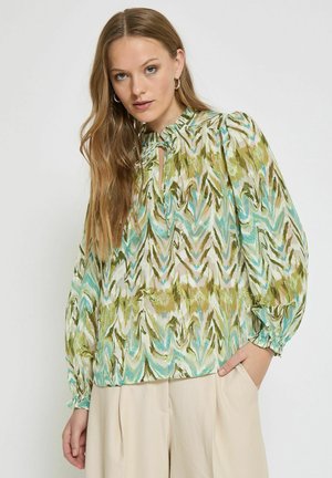 Grön och beige mönstrad blus med långa puffärmar och knytkrage. Tyget har en slät yta och har ett abstrakt mönster.