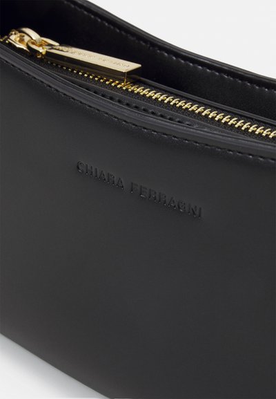 Pochette in pelle nera con zip dorata, logo "Chiara Ferragni" stampato in rilievo e texture liscia con elementi di design minimalisti.