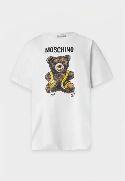 Λευκό κοντομάνικο μπλουζάκι με το κείμενο "MOSCHINO" και ένα καφέ αρκουδάκι τυλιγμένο με κίτρινη μεζούρα στο μπροστινό μέρος.