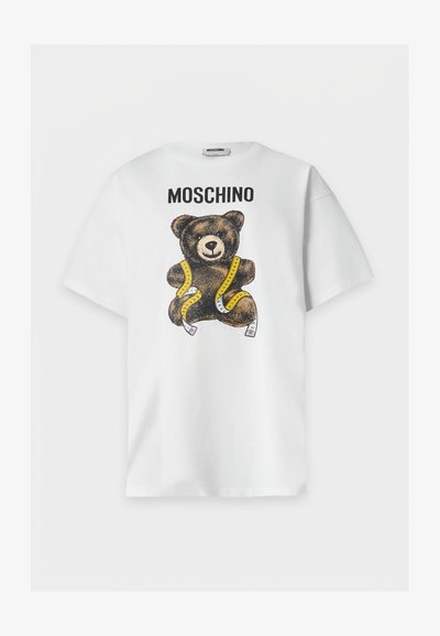 Λευκό κοντομάνικο μπλουζάκι με το κείμενο "MOSCHINO" και ένα καφέ αρκουδάκι τυλιγμένο με κίτρινη μεζούρα στο μπροστινό μέρος.