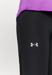 Svarta leggings med en slät textur, utrustade med en vit Under Armour-logotyp på låret och en åtsittande, strömlinjeformad design.