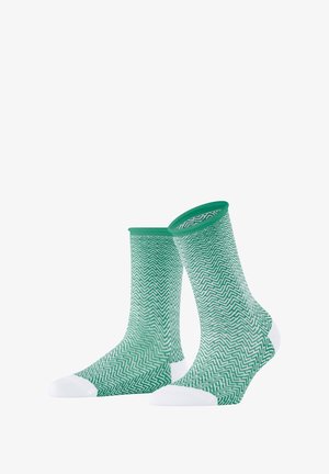 Green patterned socks with a herringbone design, featuring a solid green cuff and white toe accents. Made of soft, textured fabric.