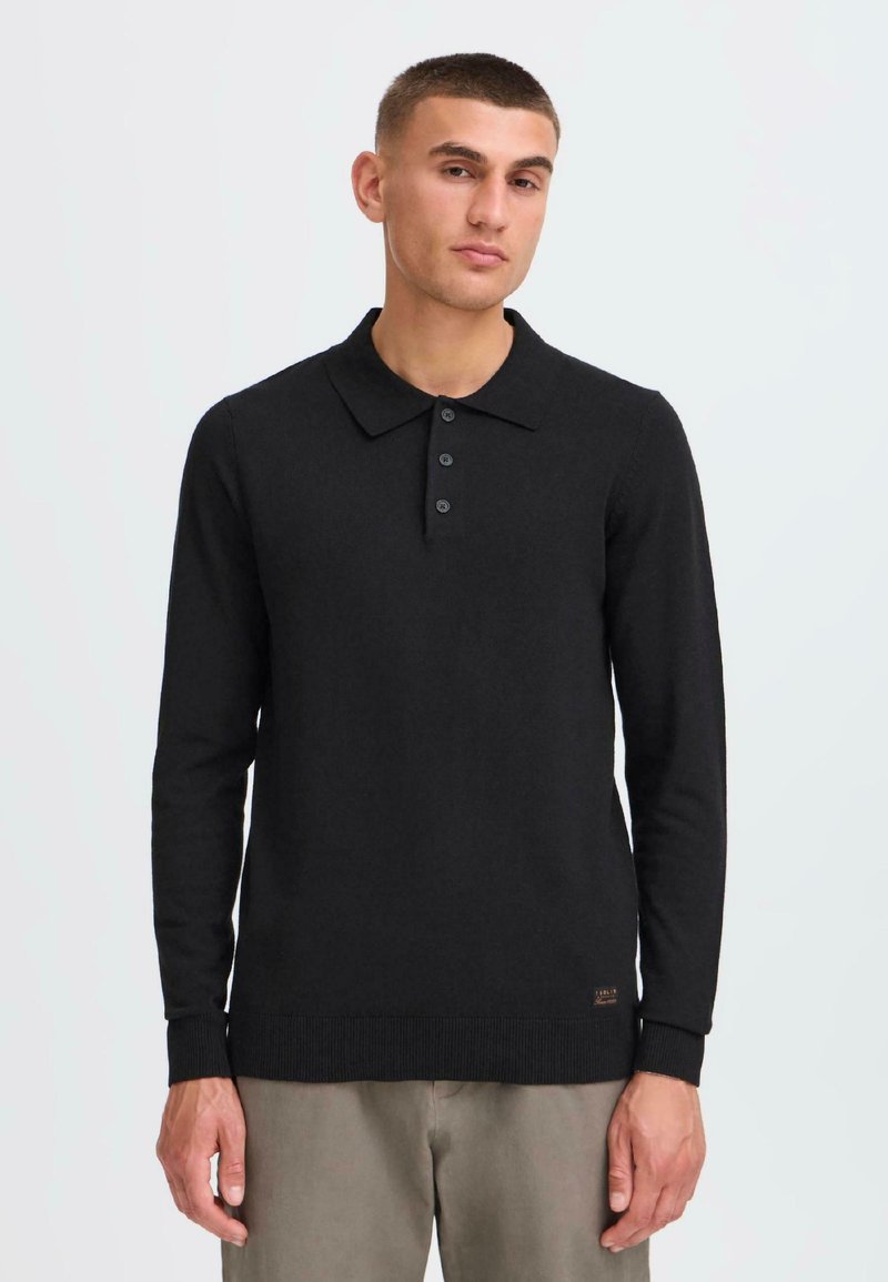 Schwarzes Langarm-Polohemd mit Kragen, ausgestattet mit einer Knopfleiste mit drei Knöpfen, gerippten Bündchen und Saum, aus einem weichen Strickmaterial.