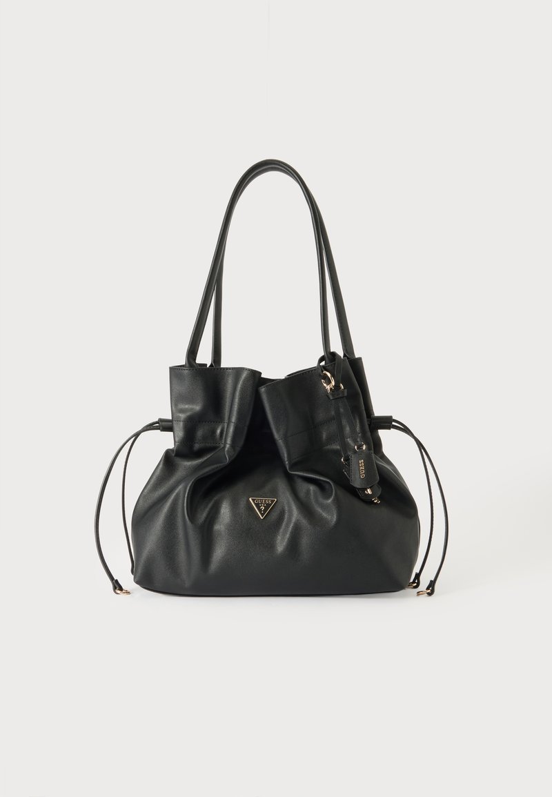 Sac à main en cuir noir avec doubles sangles d'épaule, côtés à cordon et petit logo triangulaire Guess à l'avant avec étiquette de marque attachée.