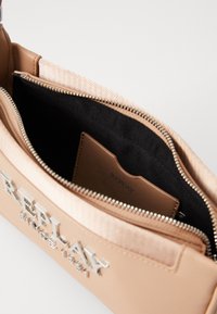 Μπεζ τσάντα χειρός με λείο εξωτερικό, ασημί αξεσουάρ και εσωτερική τσέπη με φερμουάρ. Περιλαμβάνει έναν κάτοχο καρτών με κομμένο λογότυπο που είναι ορατός μέσα.