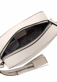 Piccola borsa in pelle beige con chiusura a cerniera superiore, dotata di una fodera a motivi scuri e di una tracolla piatta con un gancio metallico.