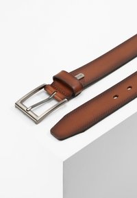 Cintura in pelle marrone con finitura liscia, dotata di una fibbia in metallo argentato e perforazioni decorative lungo la cinghia.