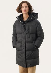 Zwarte pufferjas met een capuchon, ritssluiting en voorzak. Kenmerkt zich door een quiltpatroon en waterafstotend materiaal.
