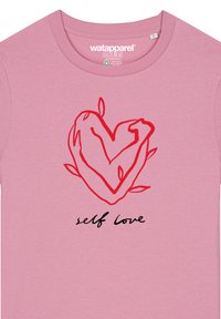 Hellrosa Baumwoll-T-Shirt mit einem roten, handgezeichneten Herzen und Blättern sowie dem Satz "Selbstliebe" in schwarzer Schreibschrift darunter.