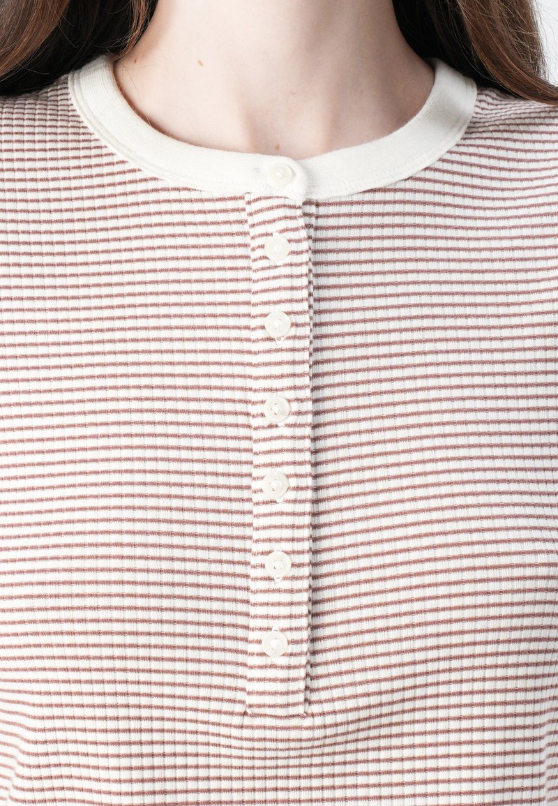 Pasiasta koszula henley w odcieniach kremu i przygaszonego różu, o strukturalnym ribbingowym wykończeniu, okrągłym dekolcie i listwie z sześcioma guzikami.