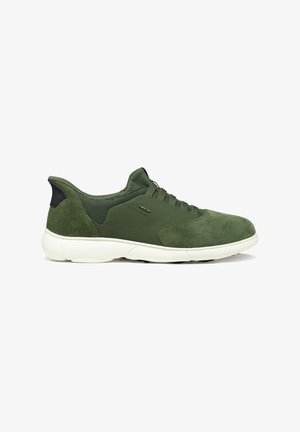 Zapatilla deportiva verde con parte superior de ante y malla, suela blanca, tobillo bajo y cordones elásticos, mostrada de perfil lateral.