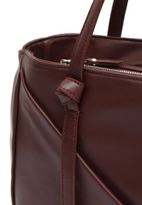 Brown leather tote bag with a textured finish, featuring a zippered top and a knotted strap detail on the side.