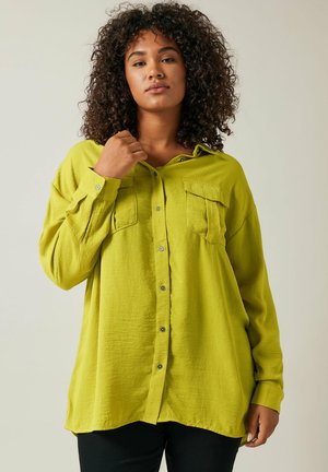 Camisa de botones verde lima con mangas largas, que presenta dos bolsillos en el pecho y un corte holgado, hecha de una tela texturizada y ligera.