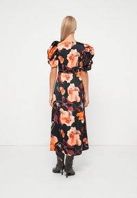 Μαύρο φλοράλ φόρεμα με πορτοκαλί και ροζ λουλούδια, φουσκωτά μανίκια, μαζεμένη μέση και ροή maxi μήκους. Φοριέται με μαύρες μπότες έως το γόνατο.