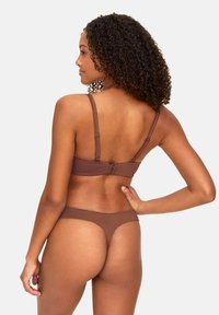 Braunes Lingerie-Set mit einem Bralette mit verstellbaren Trägern und Hakenverschluss, kombiniert mit einem passenden Tanga. Glatte Textur, reduziertes Design.