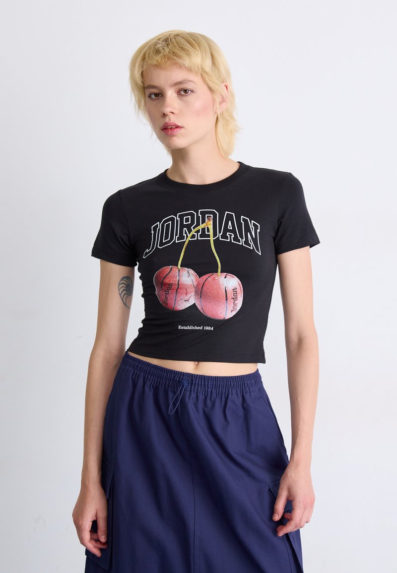Black cropped t-shirt featuring "JORDAN" text, cherry graphics, and "Established 1984." Paired with navy drawstring pants.