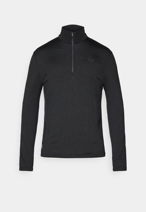 Svart langermet genser med halv-zip krage, med teksturert stoff og en liten logo på brystet. Klassisk passform med sideelementer.