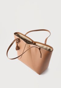 Τσάντα tote από δέρμα σε ταμπά απόχρωση με διπλά χερούλια, ανοιχτό πάνω μέρος, εσωτερική τσέπη και μικρή προσδεδεμένη δερμάτινη ετικέτα, εμφανίζεται σε απλό φωτεινό φόντο.