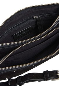 Czarna torebka zamszowa z suwakiem w kolorze złotym, wieloma przegródkami wewnątrz oraz odpinanym paskiem. Subtelny wzór w kropki na zewnątrz.