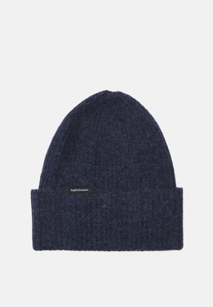 Navy knitted beanie with a ribbed cuff, made of soft wool, featuring a small black label with white text. Textured, stretchy, and warm design.
