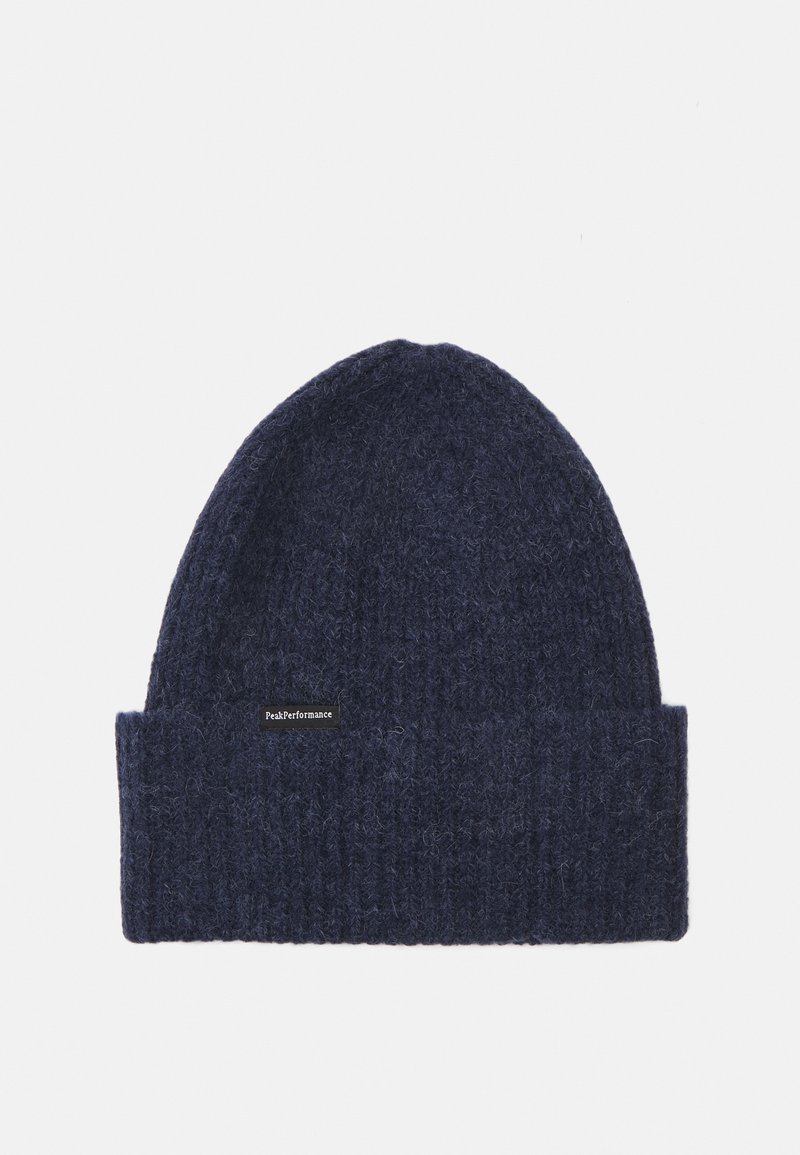 Marineblauwe gebreide beanie met een geribde rand, gemaakt van zachte wol, met een klein zwart label met witte tekst. Getextureerd, rekbaar en warm ontwerp.