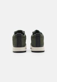 Groene sneakers met een textuurmateriaal, een gewatteerde kraag en een kenmerkende zwarte hielcounter met het "BORG"-logo. Rubberen zool voor grip.