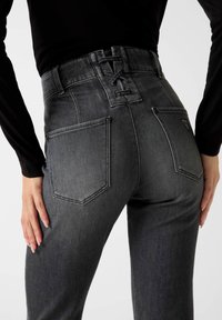Grijze jeans met hoge taille en een veterontwerp aan de achterkant, voorzien van twee achterzakken en een gestructureerde denim afwerking.