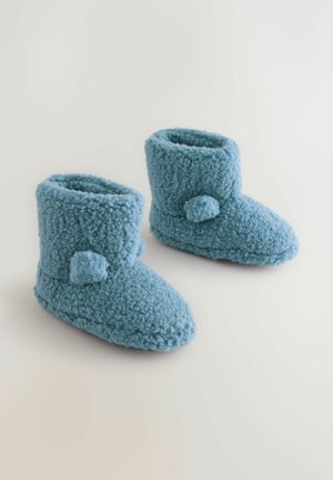 Modré měkké pantofle z nadýchaného materiálu. Výška po kotník s kulatou špičkou, zdobené dvěma bambulkami na každé straně.
