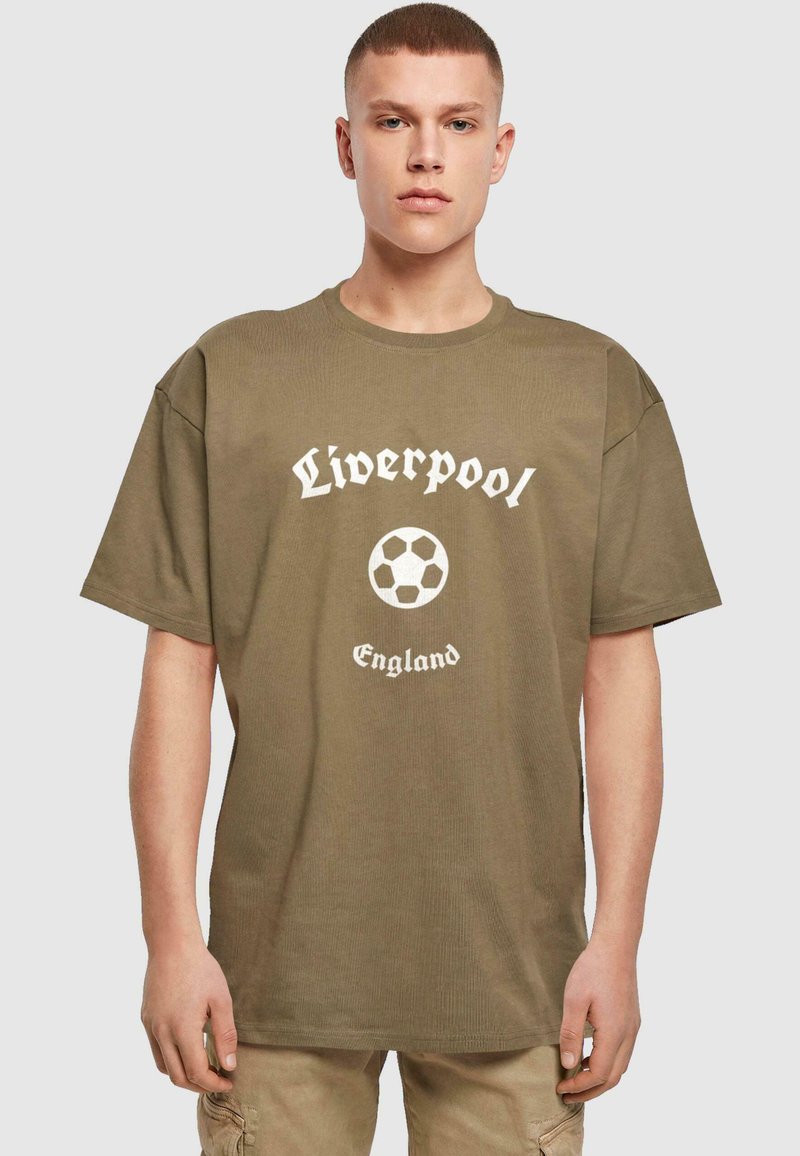 Olijfgroene katoenen t-shirt met geribbelde textuur, voorzien van een wit "Liverpool" logo en een grafische afbeelding van een voetbal, met daaronder de tekst "England".