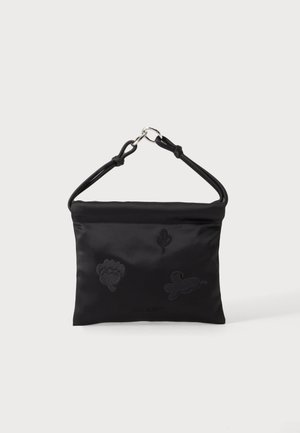 Schwarze Stoffhandtasche mit kleiner Blumenstickerei und einem kurzen Griff, der mit silbernen Ringen an schlichten weißen Hintergrund befestigt ist.