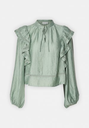 Bluză verde deschis, realizată dintr-un material texturat, cu mâneci volan, guler înalt și un detaliu legat în față. Prezintă accente din dantelă.
