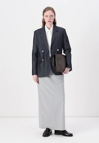 Fustă lungă gri, combinată cu un sacou din denim închis, cu nasturi dublu-pecetiți, purtată cu o cămașă albă și mocasini negri.
