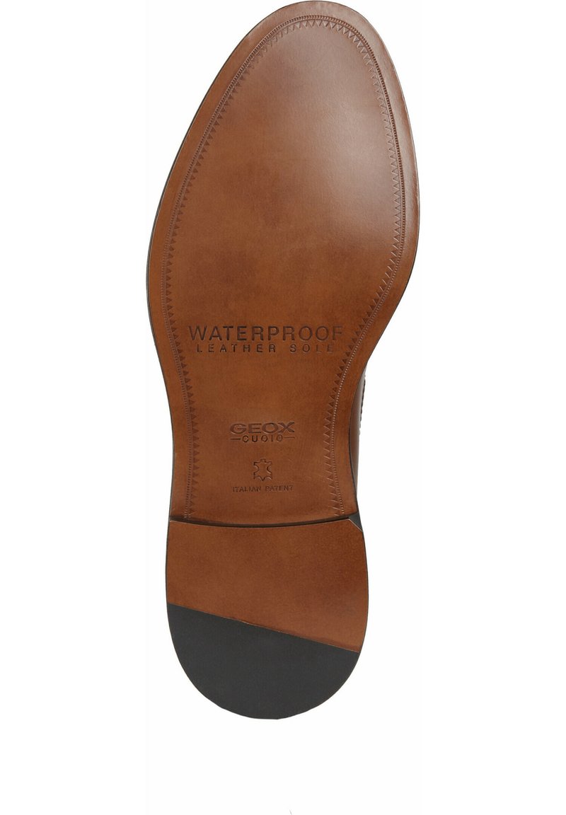 Brązowa skórzana podeszwa buta z wytłoczonymi napisami "WATERPROOF" i "LEATHER SOLE", z czarnymi gumowymi akcentami i gładkim wykończeniem.