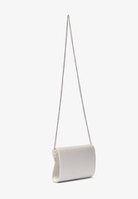 Bílá kožená kabelka do ruky s zaobleným designem, vybavená stříbrným řetízkovým popruhem a hladkou texturou. Kompaktní a minimalistický styl.