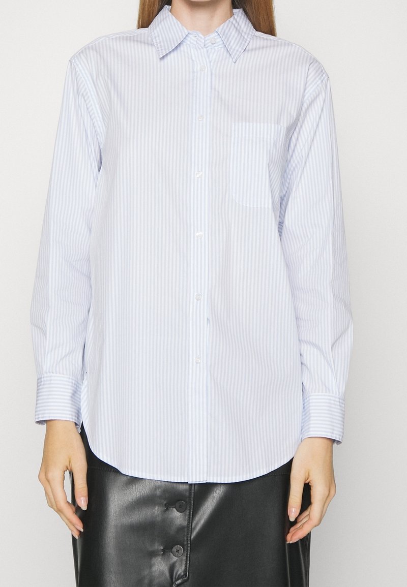 Chemise à rayures bleues claires et blanches, avec un col et une poche poitrine unique ; manches longues avec des poignets boutonnés ; en coton doux.