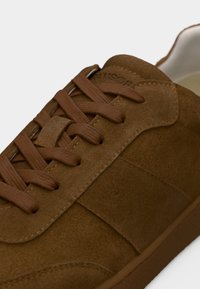 Baskets en daim marron avec lacets texturés assortis, bout rond et col rembourré. Présentent des coutures discrètes et une semelle en caoutchouc.