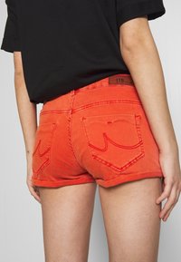 Czerwone szorty jeansowe z wysokim stanem, podwiniętymi nogawkami oraz dwoma tylnymi kieszeniami z przeszytym wzorem. Metka marki "LTB" na pasku.