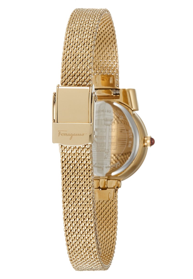 Montre avec bracelet en maille dorée et boîtier rond. Caractéristiques : fond en verre, accents dorés et petite pierre précieuse rouge sur la couronne. Design métallique épuré.