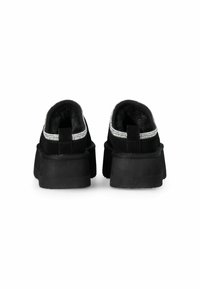 Scarpe in suede nero con suola spessa. Presentano un accento argentato sul colletto e un morbido rivestimento interno. La vista posteriore mette in evidenza la costruzione e la forma.