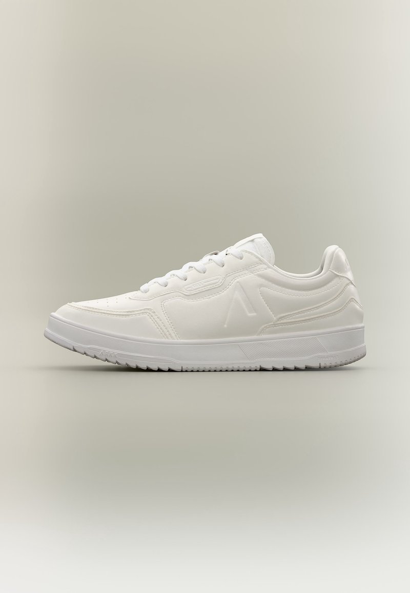 Baskets basses blanches avec lacets, semelle texturée et logo subtilement embossé sur le côté, sur un fond neutre uni.