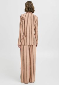 Completo due pezzi pesca con design a righe, giacca su misura con colletto a punta e pantaloni larghi con vestibilità morbida.