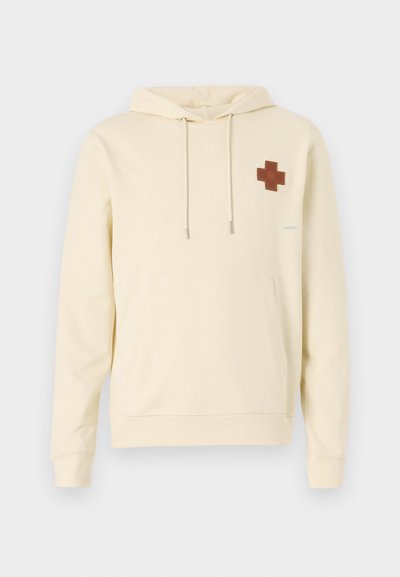 Bézs kapucnis pulóver elülső zsebbel, bal mellen barna kereszt folttal és jobb ujjon szürke részletekkel.
