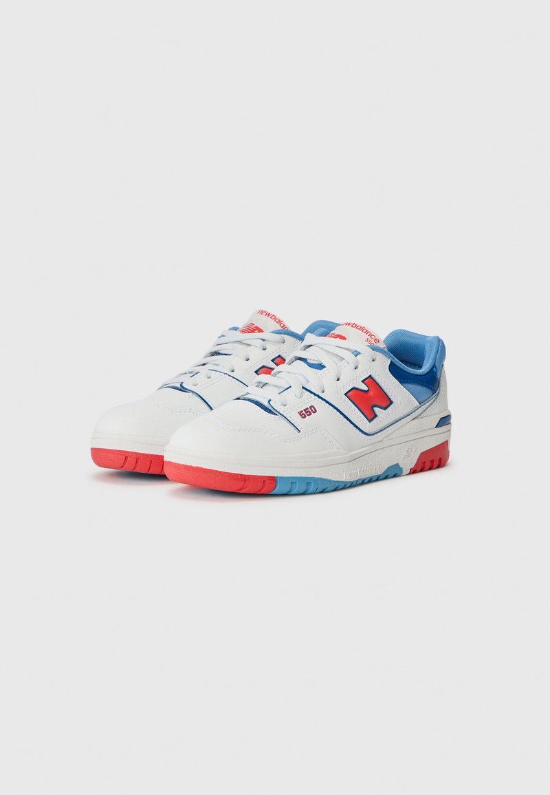 Sneakers bianchi con accenti blu e tallone rosso. Presentano un grande logo "N", una suola in gomma testurizzata e un colletto imbottito per il comfort.