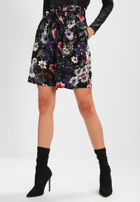 Floral shorts featuring a black background, diverse colorful flower patterns, a tie belt at the waist, and a relaxed fit.