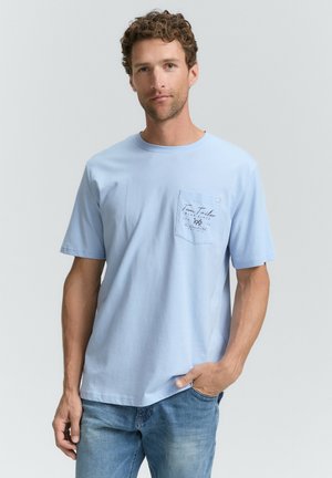 Lichtblauwe katoenen T-shirt met korte mouwen, ronde halslijn en een linkerborstzak met bedrukte tekst en logo-detail.