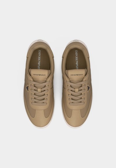 Ζευγάρι μπεζ αθλητικών παπουτσιών Emporio Armani με κορδόνια, με λογότυπο στη γλώσσα και στο πλάι, απεικονιζόμενα από πάνω σε απλό φόντο.
