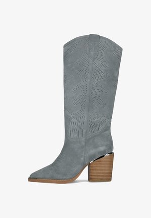 Grey suede cowboy boot with decorative perforations, pointed toe, and stacked wooden block heel.