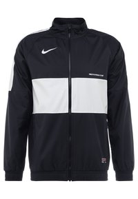 Nike voetbalclubjas in zwart en wit, gemaakt van lichtgewicht materiaal, met een ritssluiting aan de voorkant en elastische manchetten. Geaccentueerd met een logo.